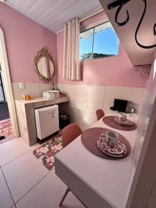 a kitchen with pink walls and a table with a coffee cup at La vita hospedaria studio Rosa in Nova Veneza