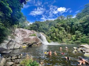 a group of people swimming in a river with a waterfall at Lagamar Eco Hotel in Cananéia
