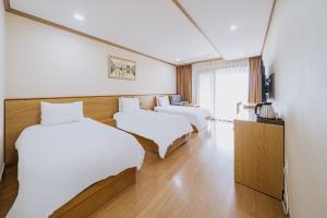 a hotel room with two beds and a television at Nohyung Hotel in Jeju