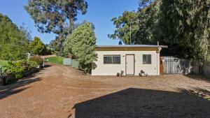 a small white shed with a driveway in front of it at Treetop Retreat Cottage in Metung