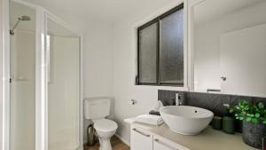 a white bathroom with a sink and a toilet at Treetop Retreat Cottage in Metung