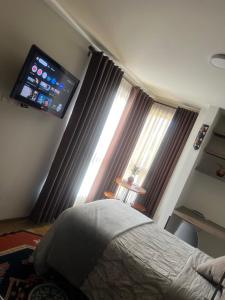 ein Schlafzimmer mit Bett und Flachbildfernseher in der Unterkunft Moderno y cómodo estudio con espacio de trabajo in Cochabamba