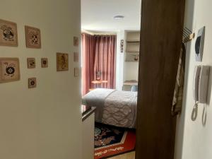 a small bedroom with a bed and a refrigerator at Moderno y cómodo estudio con espacio de trabajo in Cochabamba