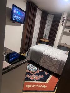 ein Hotelzimmer mit Bett und Fernseher in der Unterkunft Moderno y cómodo estudio con espacio de trabajo in Cochabamba