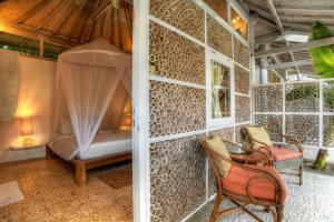 a room with a bed and a chair on a wall at Les Villas Ottalia Gili Meno in Gili Meno