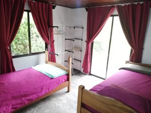 two beds in a room with red curtains at Casa el Colibrí in Naranjo