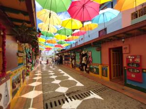 Una calle con sombrillas de colores colgando de los techos. en Aptos y Apartaestudios frente al Malecón y el Embalse, Zona Gastronómica, a 8 minutos de la Piedra del Peñol, TODO CERCA!!!, en Guatapé