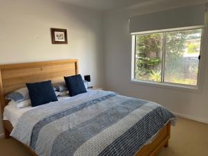 a bedroom with a bed with blue pillows and a window at Elandra House - WiFi pet friendly outside in Robe