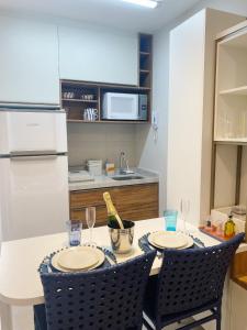 a kitchen with a table with two chairs and a refrigerator at Sunny Hall - Porto de Galinhas in Porto De Galinhas