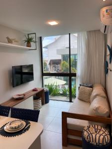 a living room with a couch and a large window at Sunny Hall - Porto de Galinhas in Porto De Galinhas