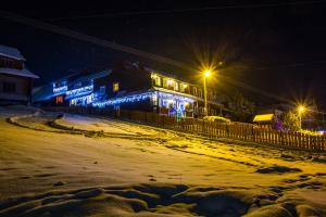 a building with lights on a snowy street at night at Penzión Blanka in Ždiar