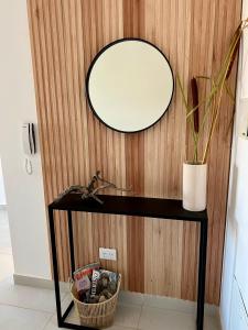 a mirror on a wall next to a table with a plant at AG Apartment in Trelew
