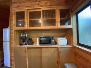 una cucina con armadi in legno e forno a microonde di プライベートヴィラ#BBQ&駐車場あり#Max6名様 a Azumaiokozan Altre 6 foto