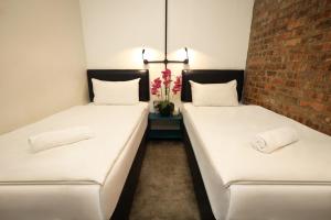 two beds in a room with a brick wall at Suite 18 Boutique Hotel in Kuala Terengganu