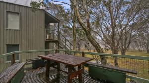 a wooden table on a deck with two benches at Pinnacle in Dinner Plain