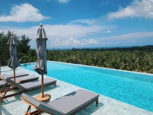 a swimming pool with chairs and umbrellas next to a swimming pool at Varivana Resort Koh Phangan, The Centara Collection in Thong Sala