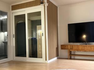 a living room with a tv and a sliding glass door at Momo House2 in Gimhae