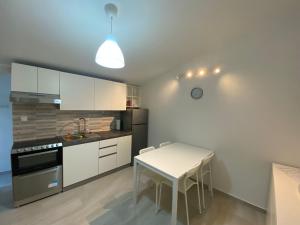 a kitchen with white cabinets and a table and a stove at Apartmani Gršćica 2 in Blato
