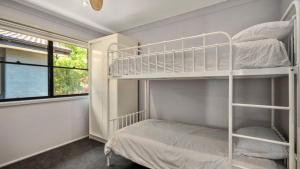 ein Schlafzimmer mit zwei Etagenbetten und einem Fenster in der Unterkunft Opal Oasis in Pearl Beach