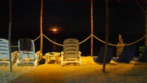three chairs and a table in the sand at night at Redang Campstay in Redang Island