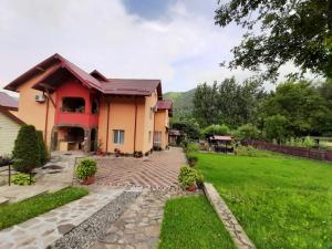 a house with a brick walkway in front of a yard at Pensiunea Sanlex in Bicaz