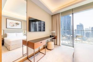 een hotelkamer met een bed en een bureau met een televisie bij Luxe 3-BR in Address Dubai Opera with Full Burj View in Dubai