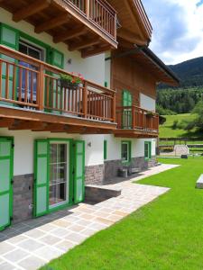 Casa con puertas verdes y balcón en Affittacamere Famiglia Ceschini, en Tesero