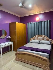 a bedroom with a bed with purple walls and a mirror at ARY&ZZ Homestay for islam guests in Tanjung Karang