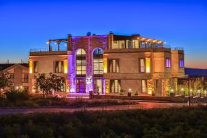 un grand bâtiment avec des lumières allumées la nuit dans l'établissement Noble Crown Stone House Cappadocia, à Uçhisar