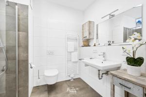 un bagno bianco con lavandino e doccia di DEIN Ostseeblick a Kappeln Altre 22 foto