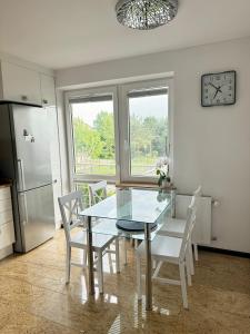 a dining room with a glass table and white chairs at Marble Apartament in Zamość