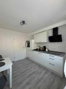 a kitchen with white cabinets and a white table at Alaras Apartment in Niederaula