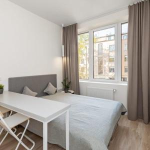 a bedroom with a bed and a table and window at Studio on Laisves Aleja, Central Kaunas - Self Check In in Kaunas