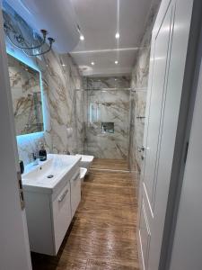 Un baño con un lavabo blanco y un espejo. en Klama Luxury Apartment, en Golem