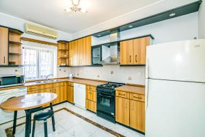a kitchen with wooden cabinets and a table and a refrigerator at Azneft Garden Apartment in Baku