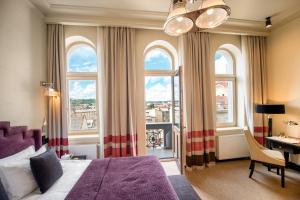 a bedroom with a bed and a desk and windows at Astoria Hotel in Lviv