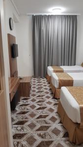 a hotel room with three beds and a television at Sama Al Amany Hotel in Makkah +13 photos