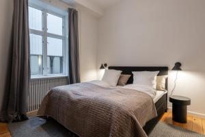 ein Schlafzimmer mit einem Bett und einem großen Fenster in der Unterkunft Stunning 5 BR Apartment by The Lakes in Kopenhagen