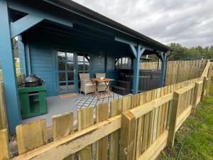 インバネスにあるRetreat Hot Tub Highland Cabinの木の柵とテーブルのある青い家