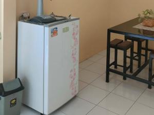 a white refrigerator in a kitchen next to a table at Sierra Homestay Malang 3 BR AC in Ngadipuro