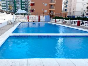 een groot blauw zwembad in een gebouw bij Apartamento Arenal 1a Linea de Playa in Cullera