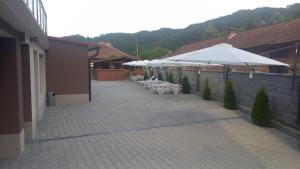 a patio with white umbrellas and tables and chairs at Къща за гости МИЧЕВИ in Shipkovo