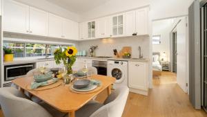 eine Küche mit einem Tisch mit einer Vase mit Blumen darauf in der Unterkunft Sunshine Cottage in Culburra Beach + 33 Fotos