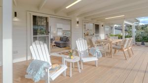 eine Veranda mit weißen Stühlen und einem Tisch auf einem Haus in der Unterkunft Sunshine Cottage in Culburra Beach