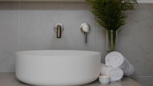 ein Badezimmer mit einem weißen Waschbecken und einer Vase mit einer Pflanze in der Unterkunft Sunshine Cottage in Culburra Beach