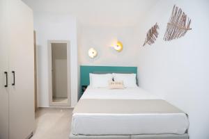 ein Schlafzimmer mit einem weißen Bett mit blauem Kopfteil in der Unterkunft Blue Sand Apartment in Pefkohori