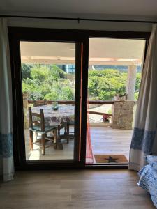 eine Glastür, die zu einer Terrasse mit Tisch und Bank führt in der Unterkunft Oasi del Relax - Seaside Peaceful Panoramic Terrace in ITALY - new Sardinia apartment 50 mt beach&sea full comfort air conditioning-WiFi-Parking-Privacy in Torre Dei Corsari