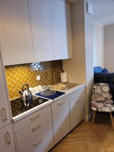 a kitchen with white cabinets and a stove top oven at Apartament Diuna in Krynica Morska