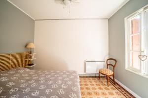 a bedroom with a bed and a chair and a window at Le Havre Catalan - Maison pour 6 à Argelès-sur-mer in Argelès-sur-Mer