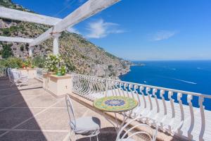 a balcony with a table and chairs and the ocean at Villa Cristina -No steps-Amalfi Coast Views -Hot tube in Praiano